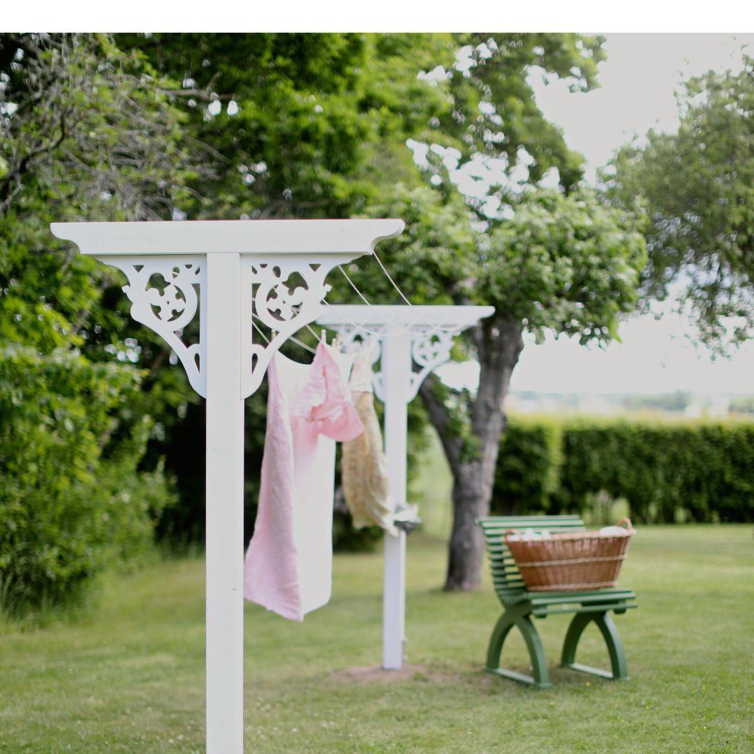 Bild på en komplett torkställning med hängande tvätt. Vid sidan står en tvättkorg på en grön trädgårdsstol från Carlshaga 