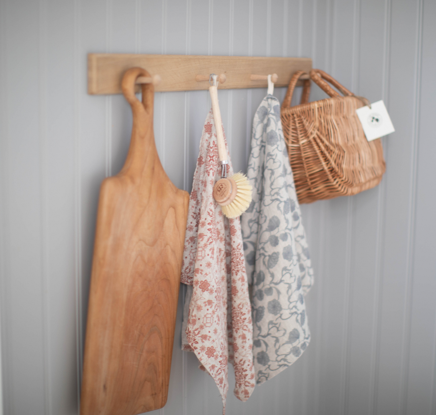 Dekorativ knopplist med hängande skärbräda, handduk och vykort.