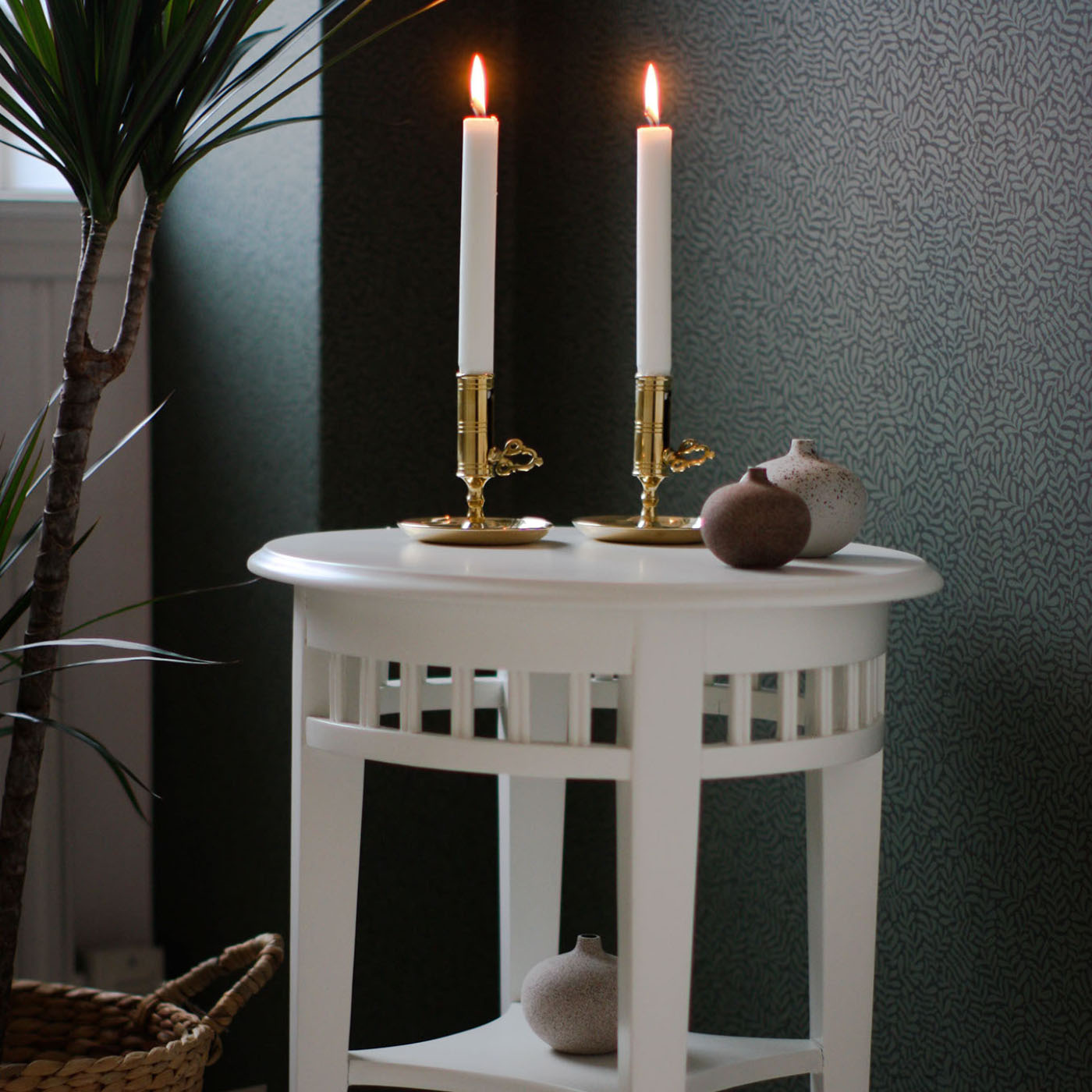 Två mässingsljusstakar på vitt runt bord 