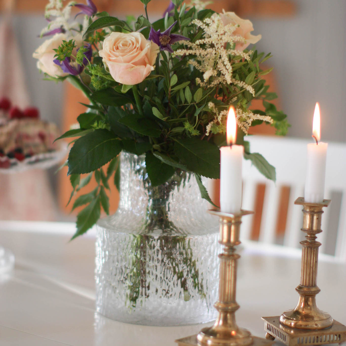 Vas från Skrifs med vackra blommor på vitt bord och ljus från Carlshaga 